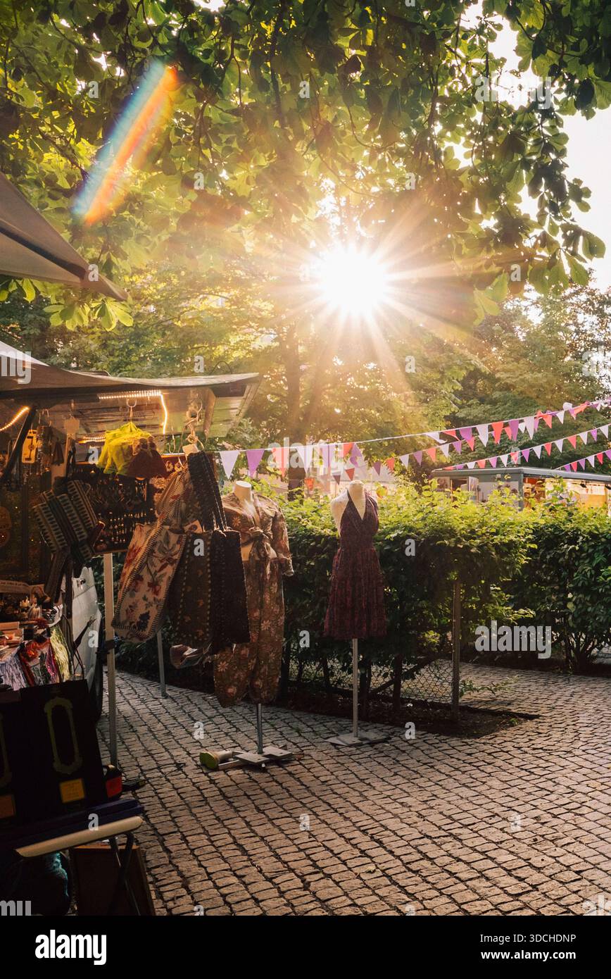 Die Sonne scheint durch Bäume über dem Kleiderladen auf der Straße Stockfoto