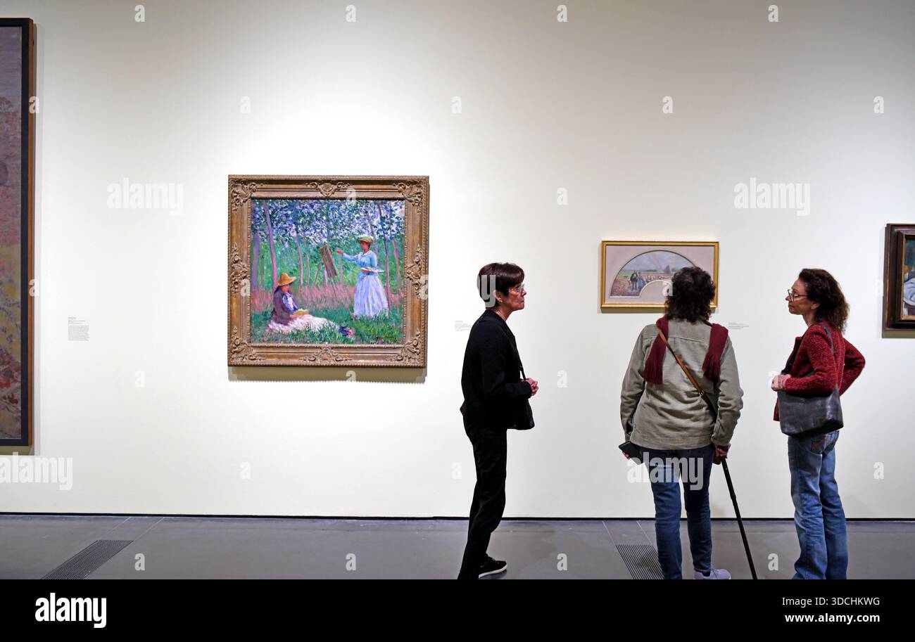 Eine Gruppe von Besuchern, die in der Nähe eines großen Gemäldes von Claude Monet in einer Kunstausstellung mit dem Titel „Sammeln des Impressionismus“ im Los Angeles County Museum of Art in Los Angeles, Kalifornien, USA, stehen Stockfoto