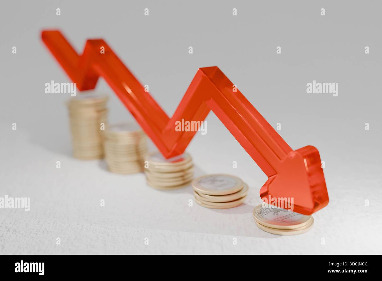 Abnehmende Münzstapel mit einem roten Pfeil nach unten veranschaulichen wirtschaftlichen Rückgang, Inflationsauswirkungen, Wertverlust und Finanzkrise. Symbol für shr Stockfoto