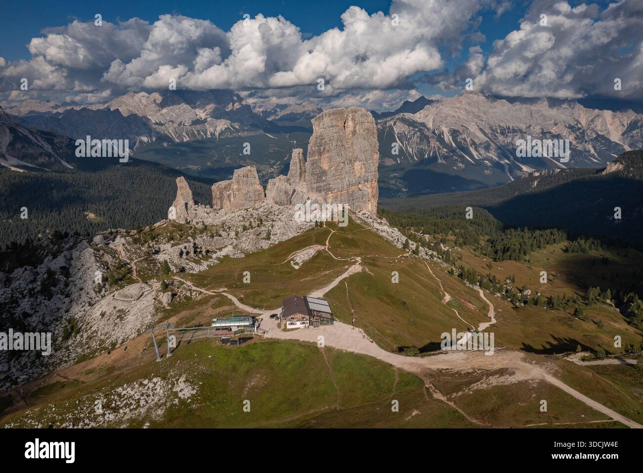 Aus der Vogelperspektive auf die zerklüfteten Gipfel von Cinque Torri, die in den Himmel ragen, inmitten eines Wandteppichs aus grünen Wiesen und zerklüftetem Gelände, Venetien, Italien. Stockfoto