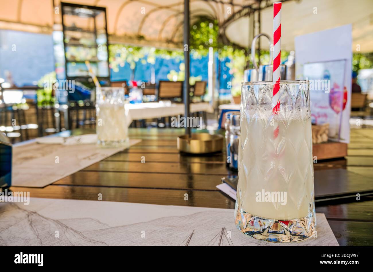 Ein erfrischendes Limonadengetränk in einem Glas mit rot-weiß gestreiftem Strohhalm. Stockfoto
