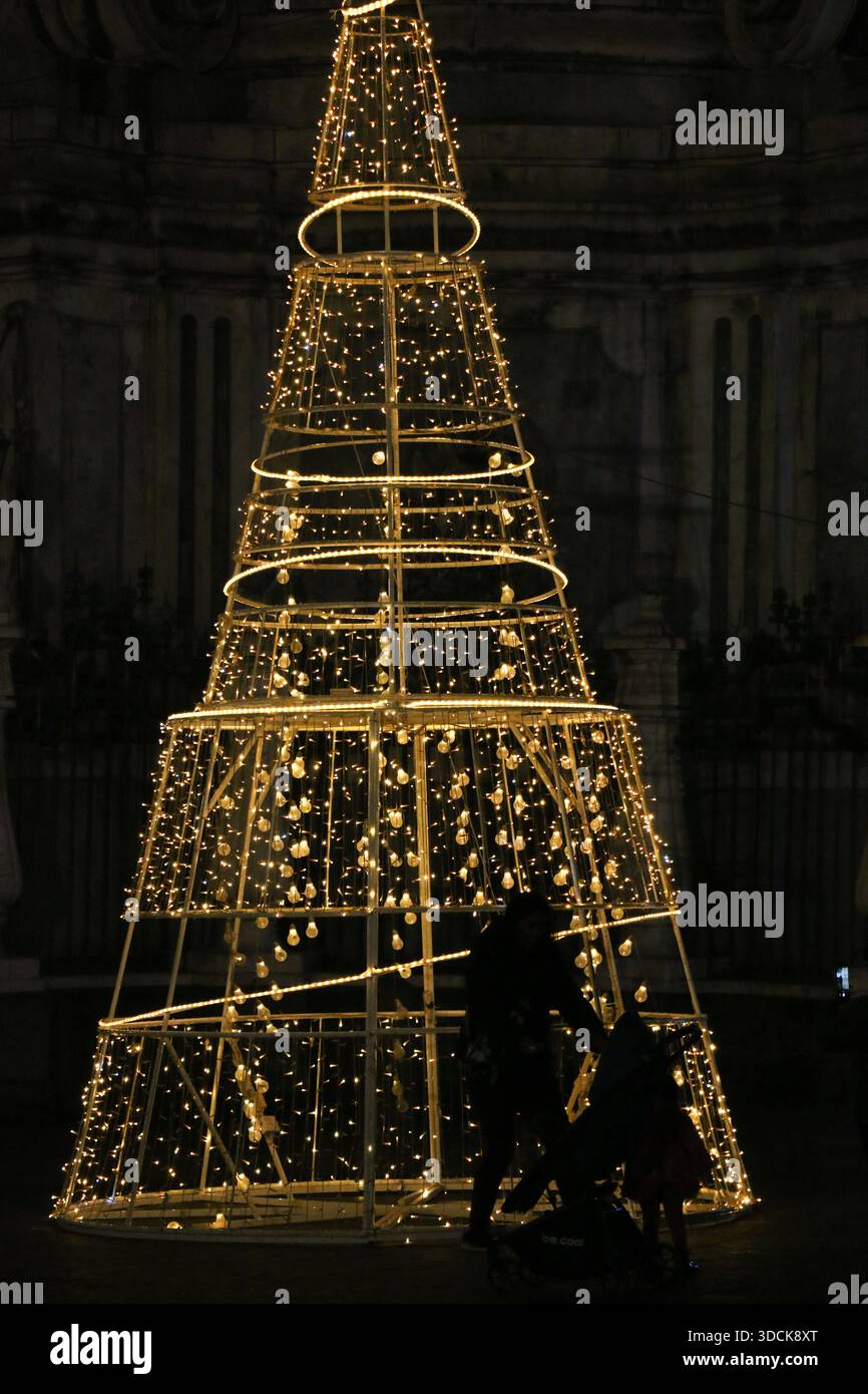 Beleuchteter Weihnachtsbaum, Stadt, glühende goldene Lichter in der Nacht, vorbeiziehende Menschen, Winter. Stockfoto