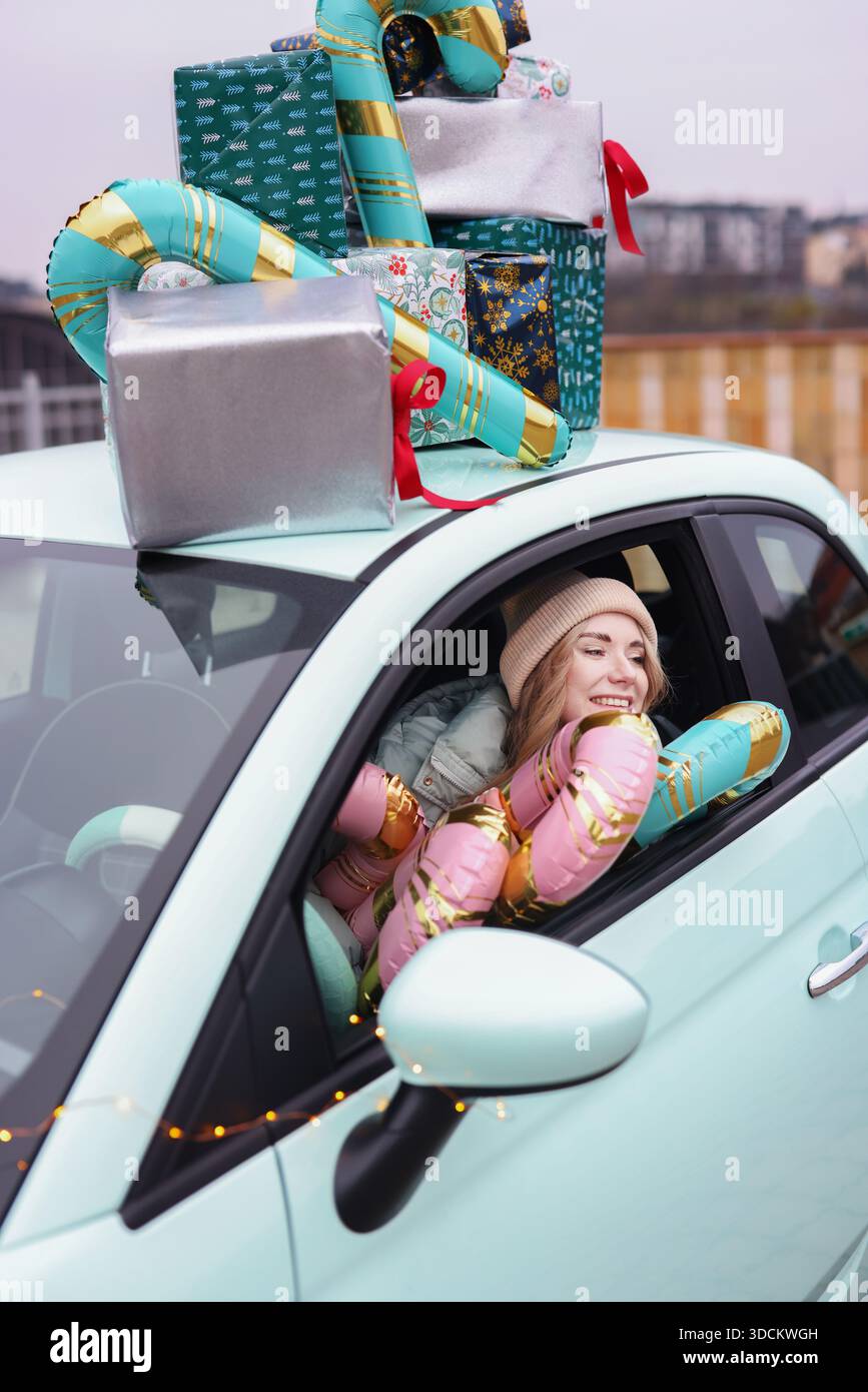 Fröhliche Weihnachtsstimmung mit Frau im Auto voller Geschenke, perfekt für Weihnachtsmarketing saisonale Verkäufe und Festthemen. Hochwertige Fotos Stockfoto