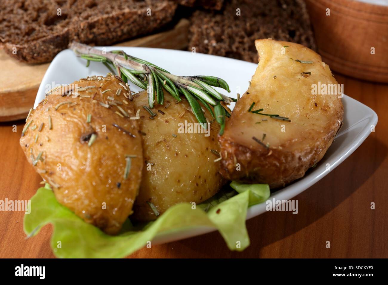 Köstliche Röstkartoffeln garniert mit Rosmarin und serviert mit Salat. Stockfoto