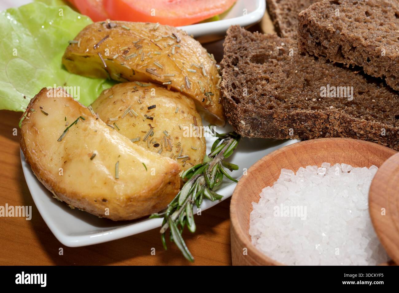 Goldene gebratene Kartoffeln, garniert mit Kräutern, knusprigem Salat und Brot. Stockfoto