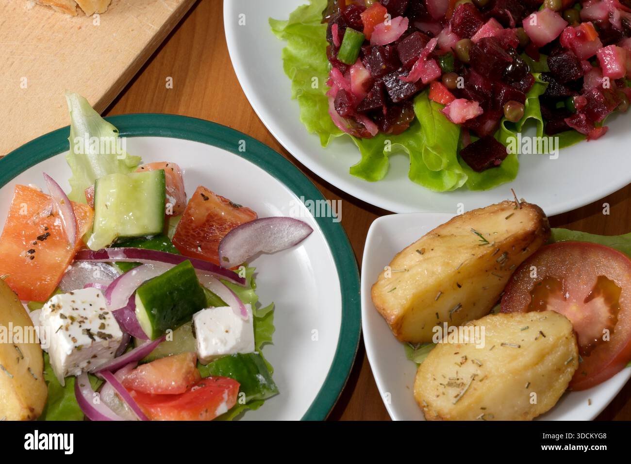Bunte Salate und goldene Kartoffeln laden die Sinne an einem freundlichen Esstisch ein. Stockfoto