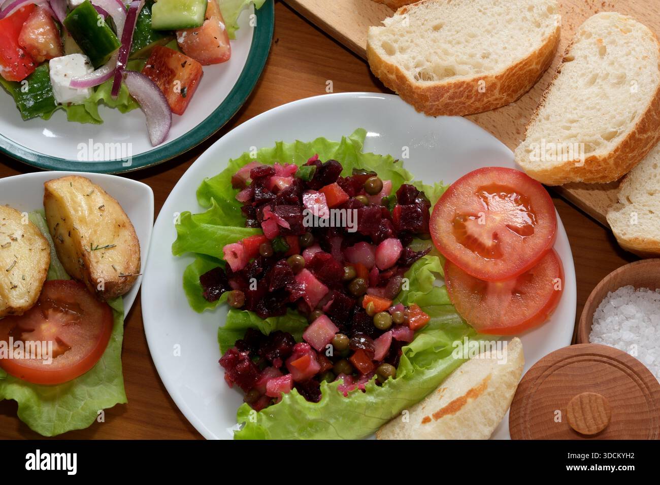 Bunte Salat- und Kartoffelgerichte auf einem rustikalen Tisch, perfekt zum Teilen. Stockfoto