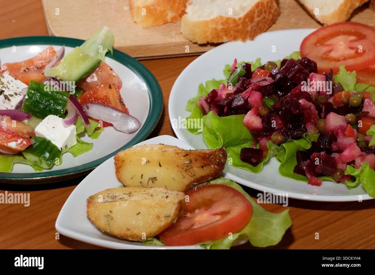 Eine bunte Auswahl an Salaten und Brot, wunderschön auf einem Tisch angeordnet. Stockfoto