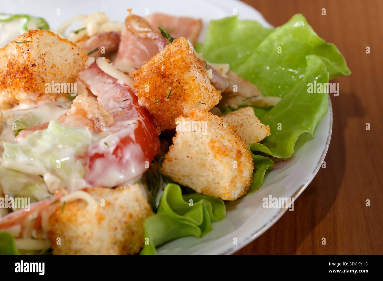 Frisches Gemüse mit Croutons, Tomaten und herzhaftem Dressing ist ein köstliches Gericht. Stockfoto