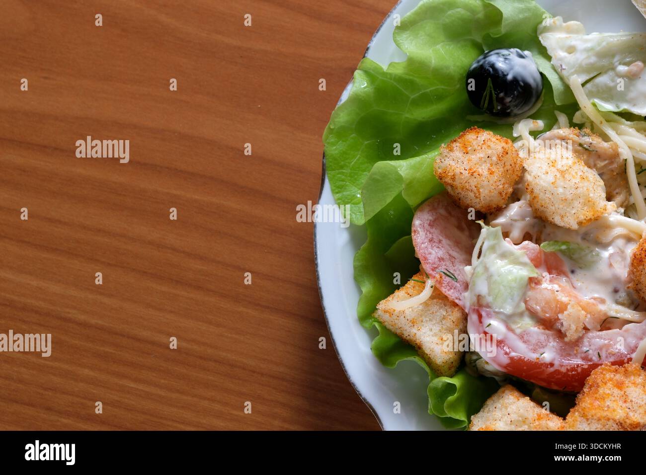 Lebendiger Salat mit Salat, Tomaten, Gurken und Croutons auf einem Holztisch. Stockfoto