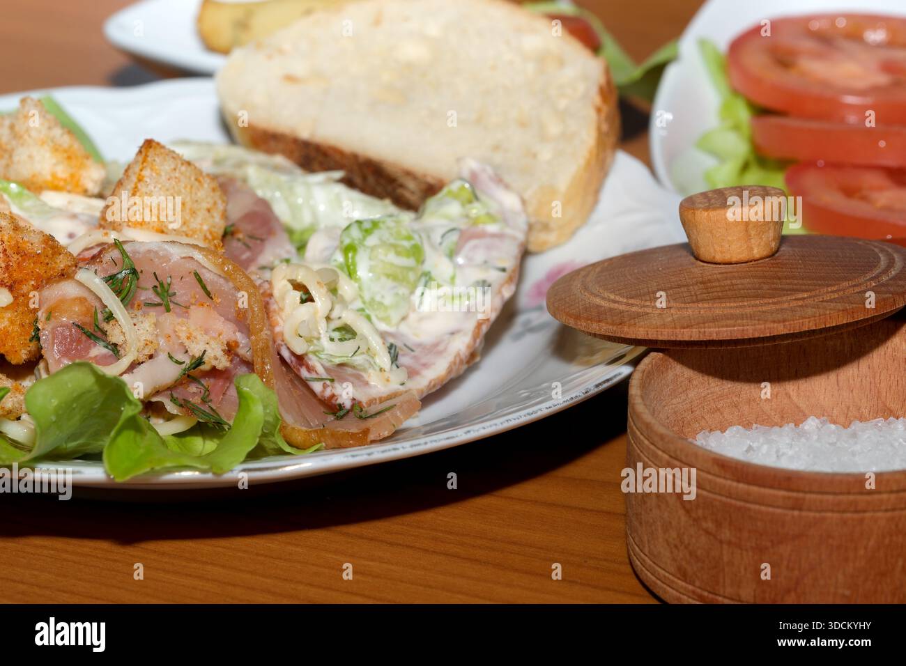 Frisches Gemüse mit herzhaftem Fleisch und cremigem Dressing erwarten Sie auf einem Holztisch. Stockfoto