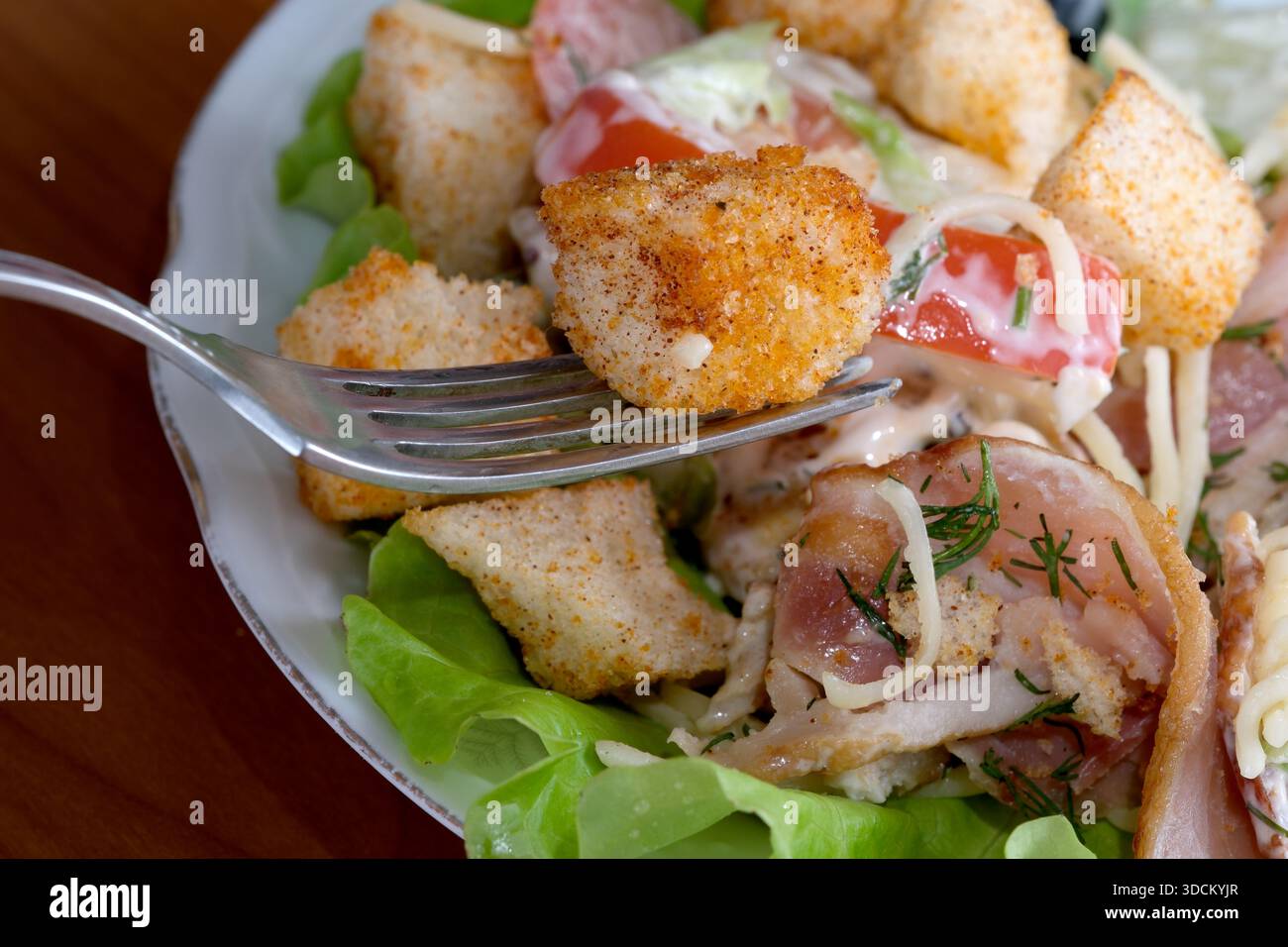 Ein gemischter Salat mit lebhaftem Gemüse und goldenen Croutons auf einem gemütlichen Tisch. Stockfoto