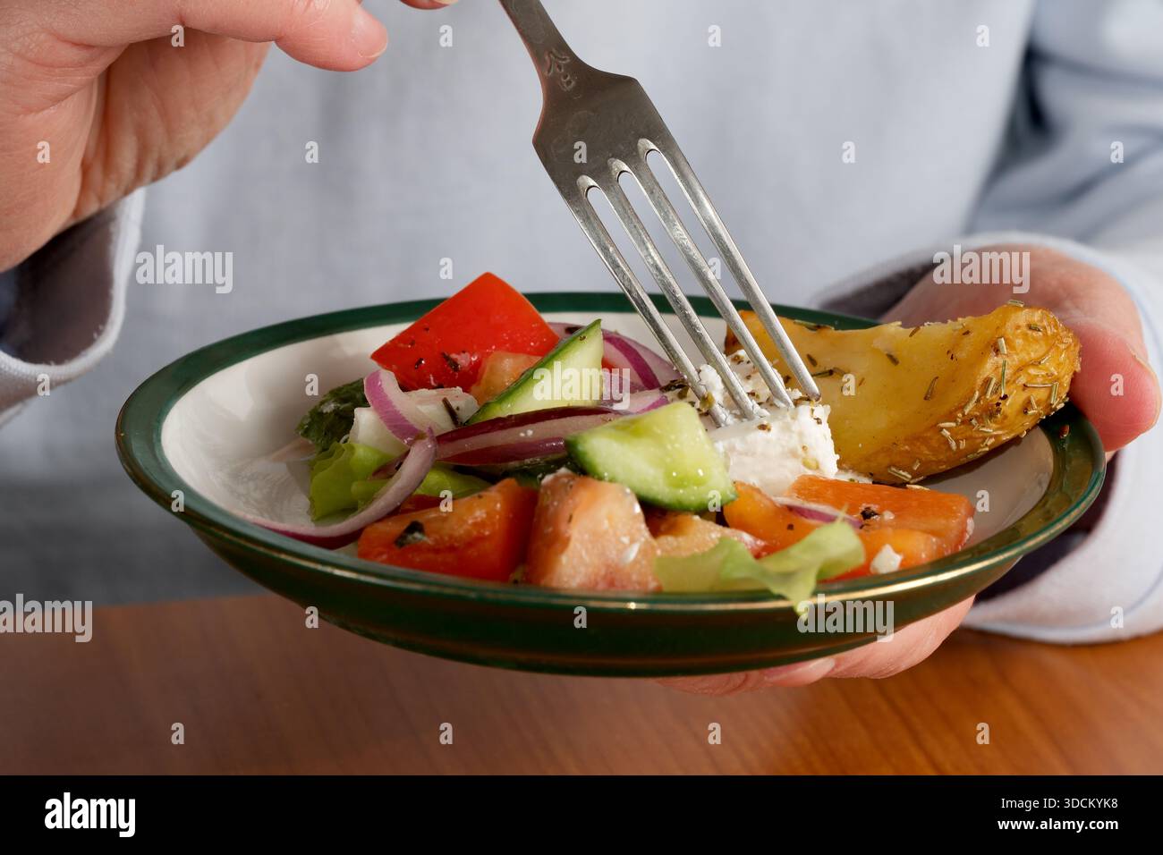 Eine Person genießt einen frischen Salat mit Gemüse und Käse und schmeckt jeden Bissen. Stockfoto