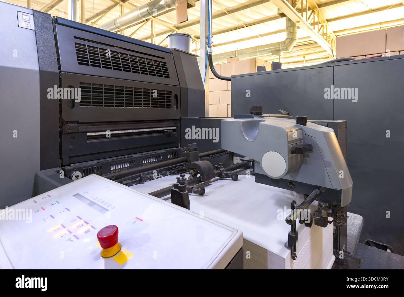 Der Papierladebereich einer großen Offsetdruckmaschine mit einem hohen Stapel weißer Blätter, die produktionsbereit sind. Stockfoto