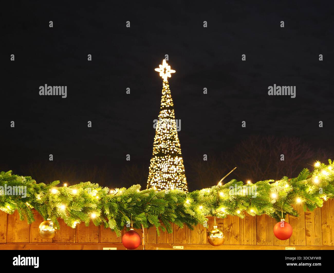 Beleuchteter Weihnachtsbaum bei Nacht mit festlicher Girlande, Ornamenten und Weihnachtsbeleuchtung Stockfoto