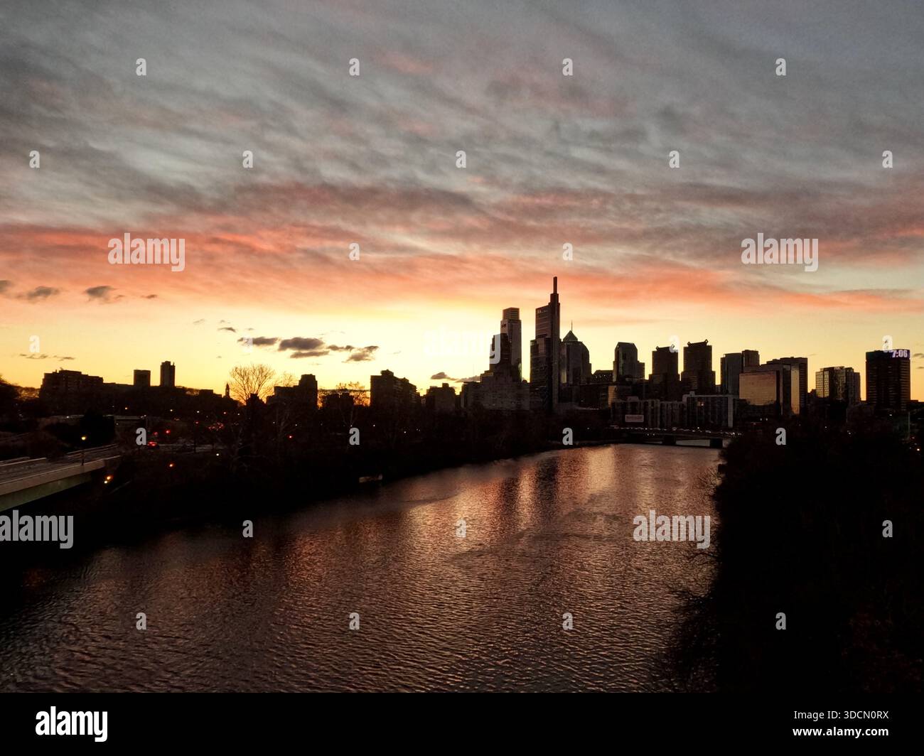 Der Sonnenaufgang beleuchtet den östlichen Himmel entlang der Skyline von Philadelphia, von der Spring Garden Street Bridge aus gesehen. Stockfoto