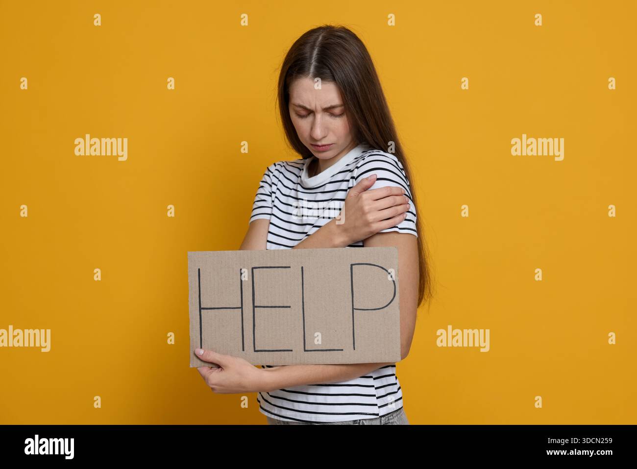 Besorgte Frau, die ein Schild mit Worthilfe auf gelbem Hintergrund hält Stockfoto