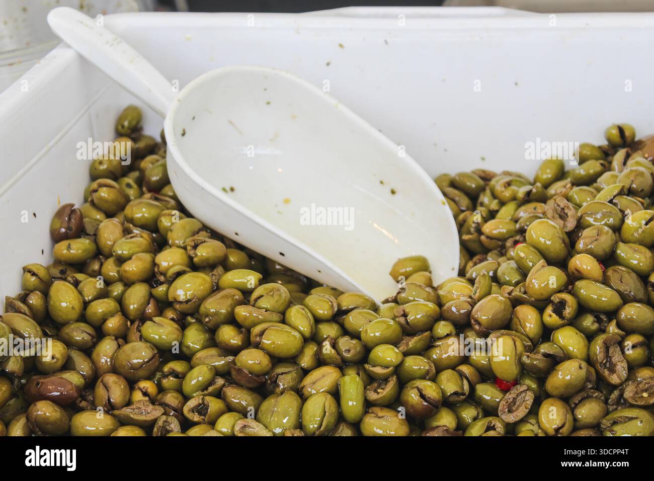 Grüne eingelegte Oliven werden auf einem Street Food Markt präsentiert, mit mediterranen Aromen, traditioneller Esskultur und lebhafter Marktatmosphäre Stockfoto