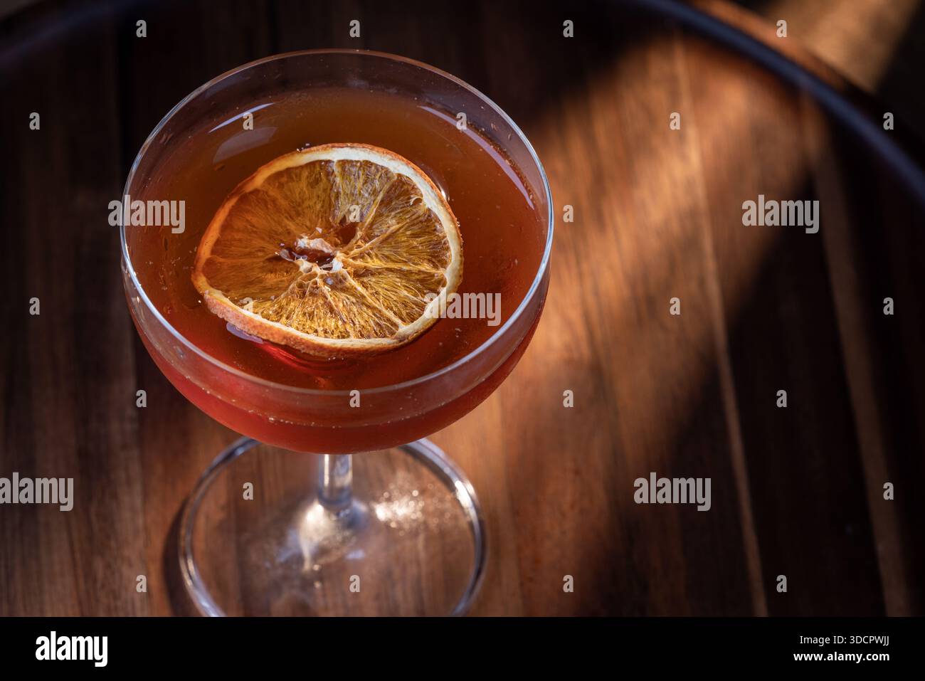 Whiskey-Cocktail oder manhattan serviert mit einer dehydrierten Orangenscheibe. Stockfoto