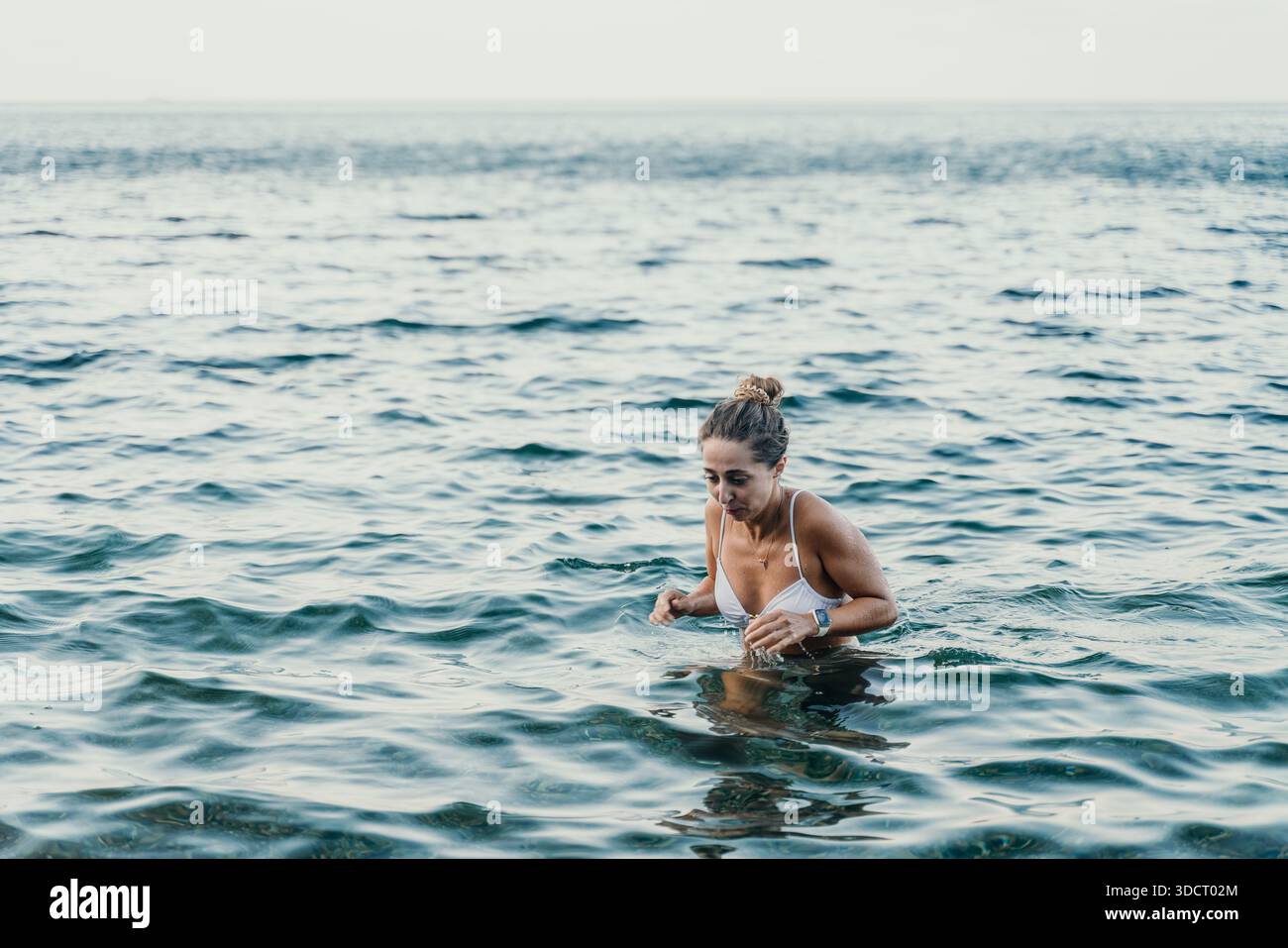 Frau Ozeanwasser, junge Frau, die während der Sommerferien aus erfrischendem Meerwasser auftaucht, mit Kopierraum. Stockfoto