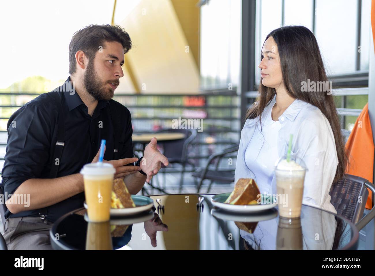 Mann und Frau reden und trinken im Café im Freien Stockfoto