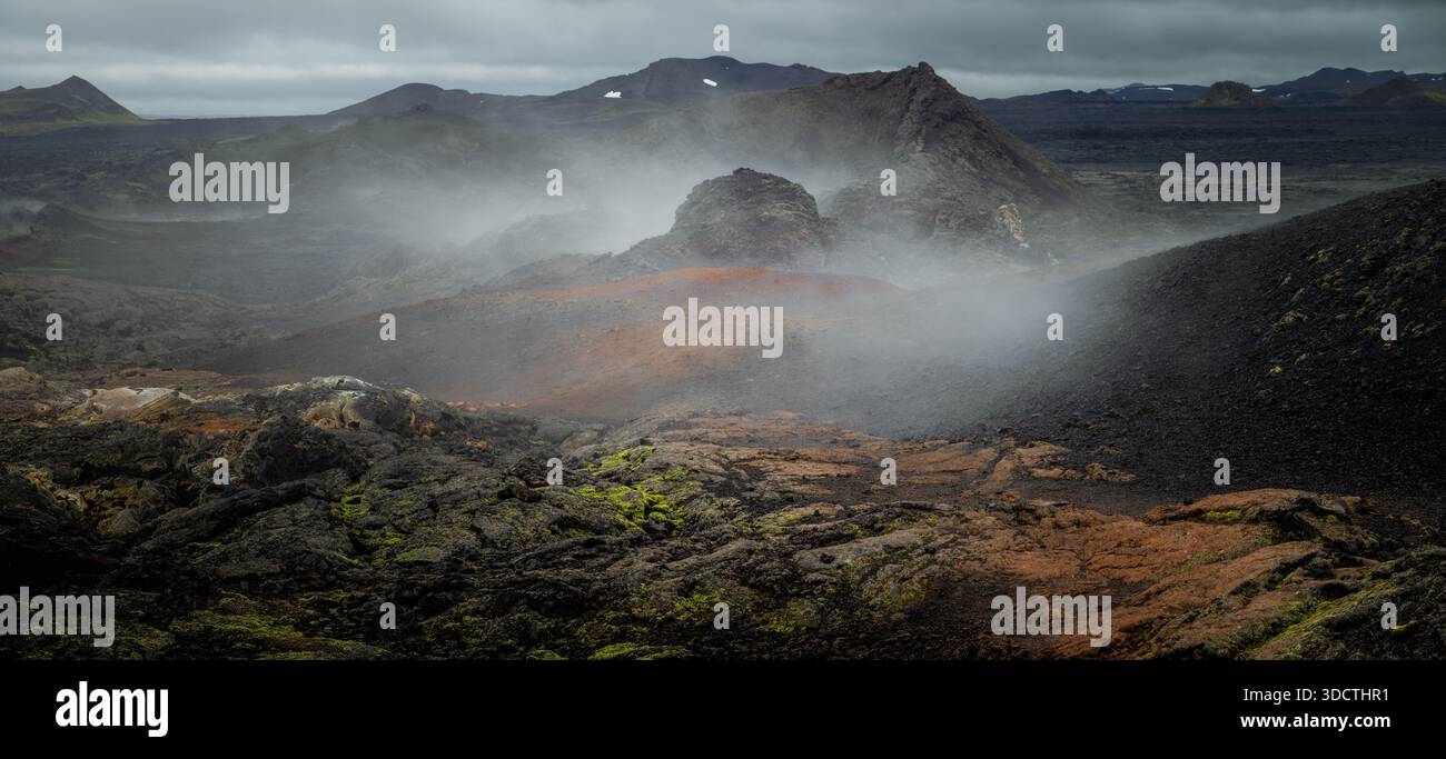 Panoramablick auf die Lavafelder des Vulkans Krafla mit Rauch, der aus der Erde steigt. Stockfoto