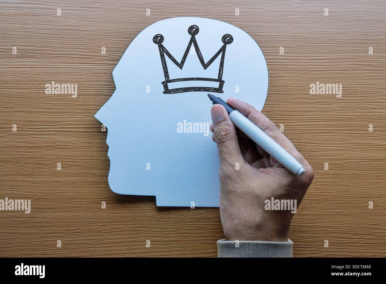Konzeptuelles Bild einer Hand, die eine Krone in einem Kopf zeichnet. Narzissmus, Ego, Selbstbedeutung, psychische Gesundheit und Überlegenheit Komplexkonzept. Stockfoto