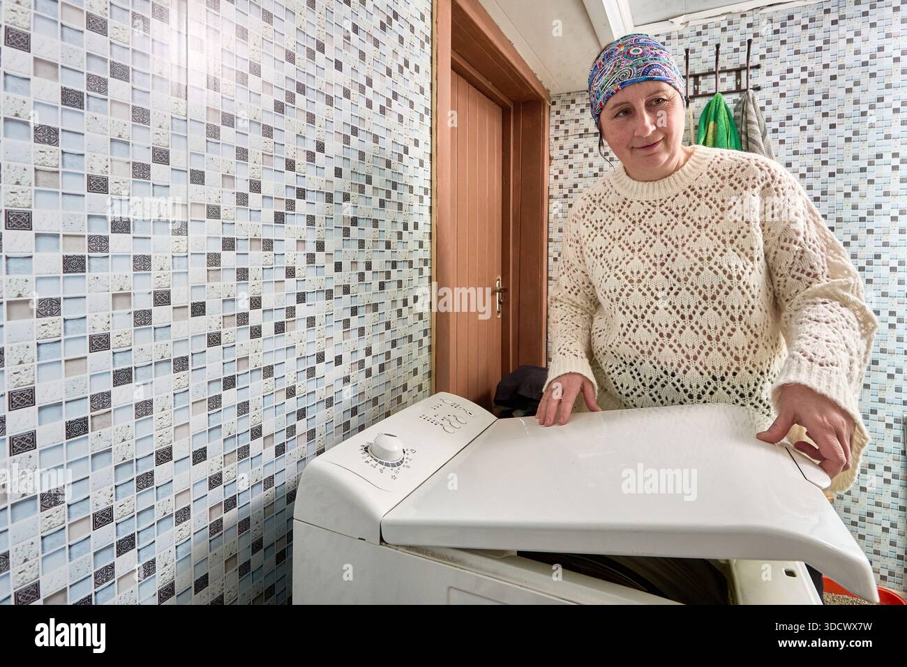 Laden der vertikalen Waschmaschine mit Wäscherei Hausfrau schließt den Deckel mit Verriegelungsmechanismus. Stockfoto