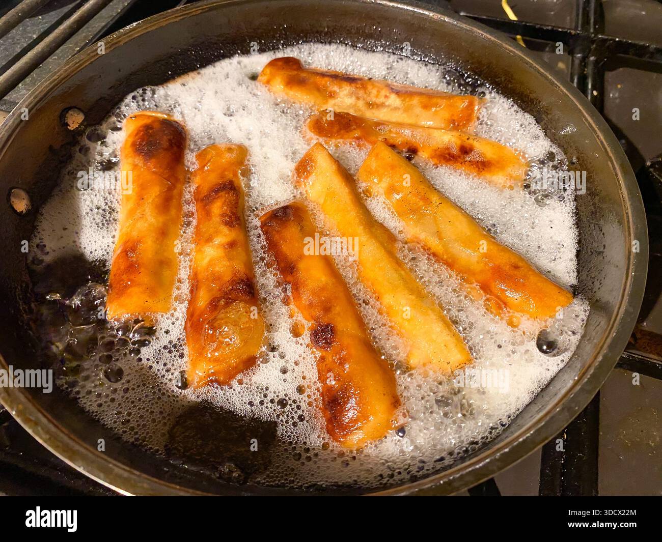 Frühlingsrollen in einer Pfanne mit heißem Öl frittieren - Smartphone-aufgenommenes Stockfoto