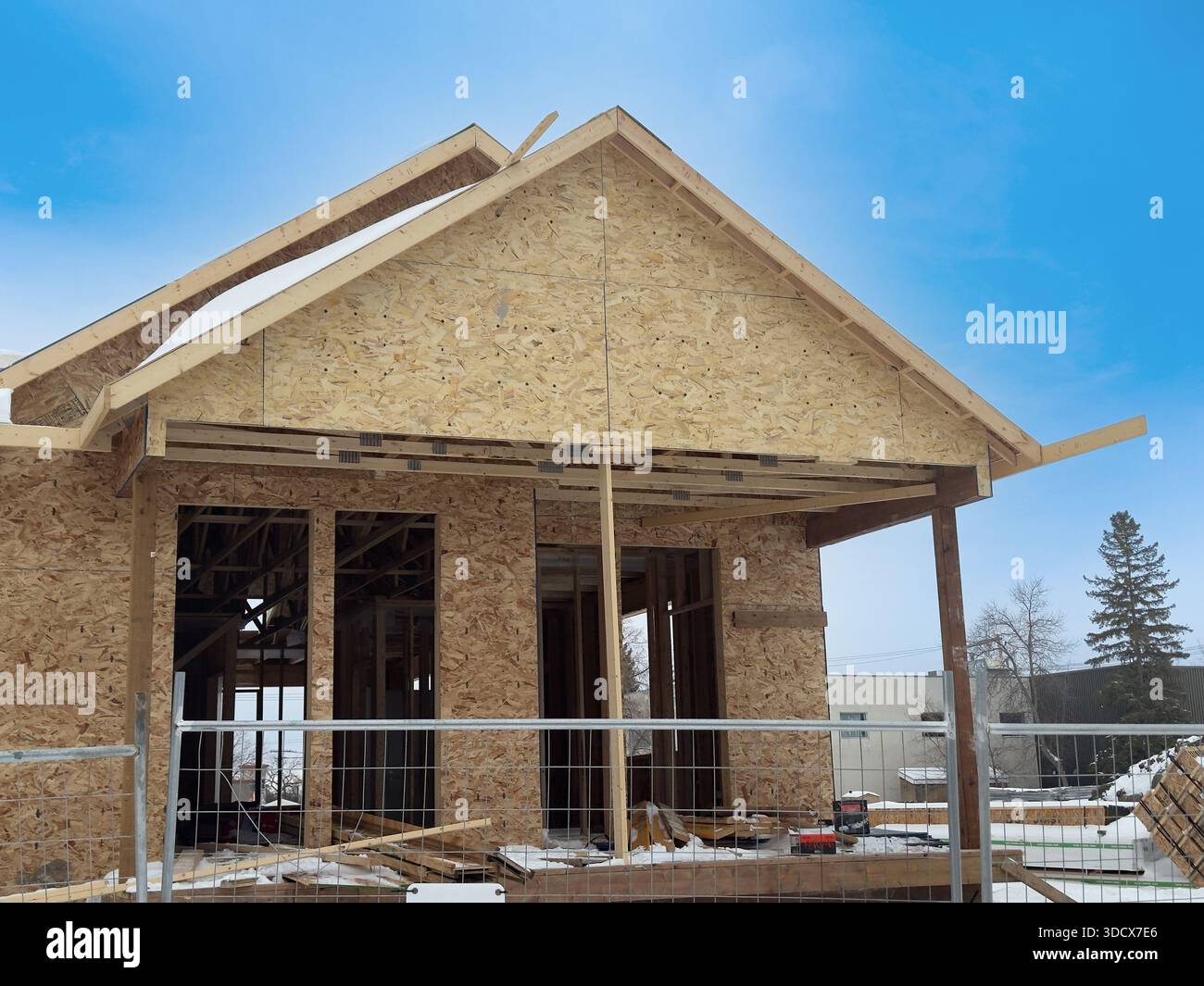Holzhausrahmen im Bau. Frühes Wohngebäude mit freiliegenden Holzrahmen und Dachstühlen an einem klaren Tag, was Fortschritte zeigt Stockfoto