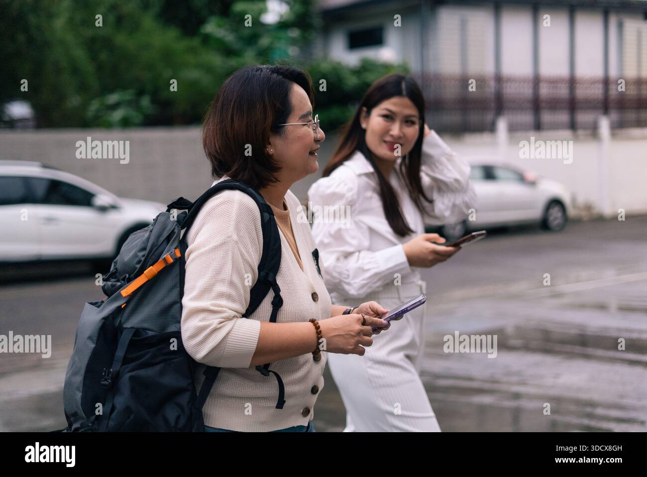 Asiatische Frauen gehen auf der Straße mit Smartphones mit Rucksacktechnologie Stockfoto