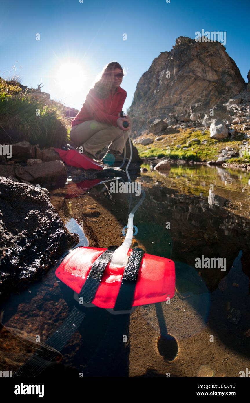 Eine junge Frau filtert Wasser, während sie im Grand Teton National Park, Jackson Hole, Wyoming, unterwegs ist. Stockfoto
