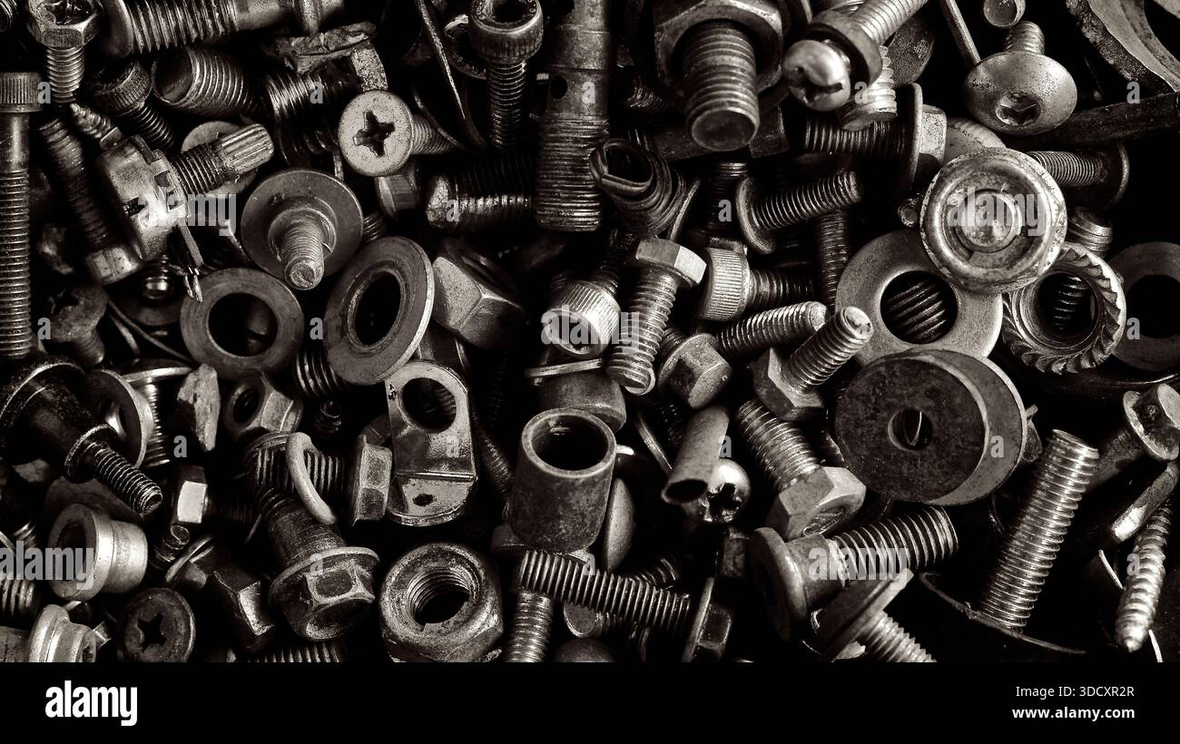 Dieses Schwarzweiß-Foto zeigt ein eng gepacktes Sortiment an Metallbefestigungen – Schrauben, Bolzen, Muttern, Unterlegscheiben und andere Hardware-Komponenten. Stockfoto