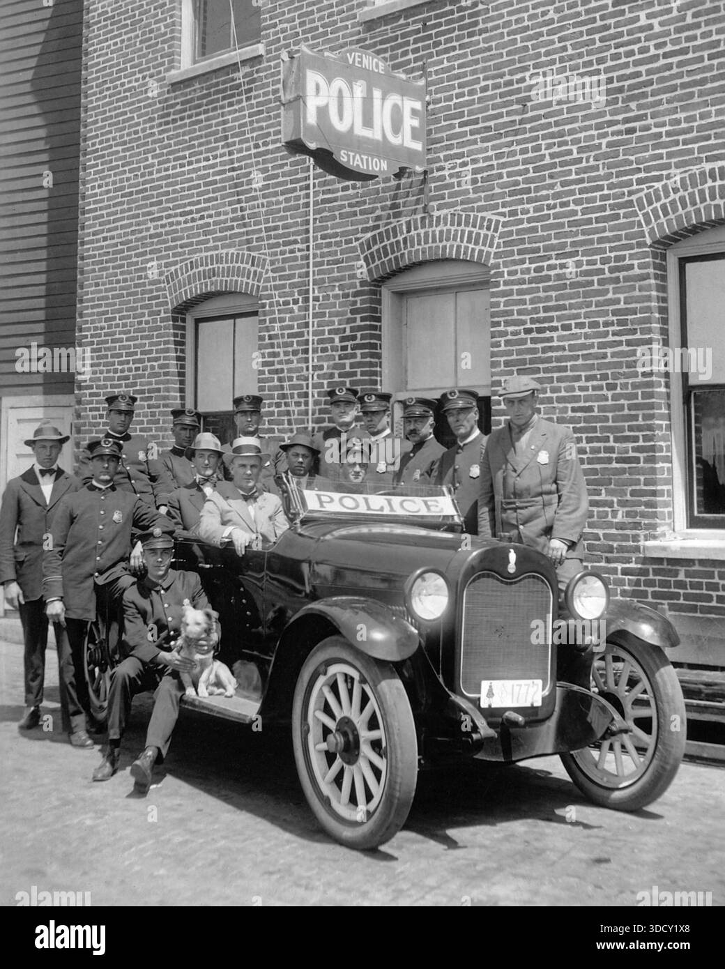 15 uniformierte Polizisten versammeln sich um einen Polizeiwagen neben der Venice Police Station, CA.1920, Los Angeles, Kalifornien. Stockfoto