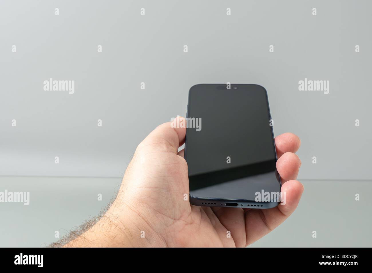 Die Hand hält ein modernes Smartphone mit leerem schwarzen Bildschirm vor neutralem Hintergrund. Das Bild weist auf Benutzerfreundlichkeit, Mockup der Benutzeroberfläche und alltägliche Nutzung hin Stockfoto