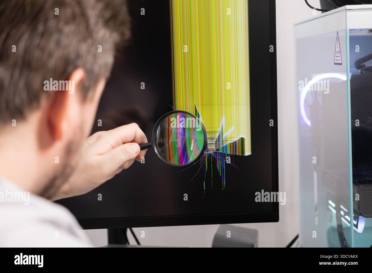 Nahaufnahme-Techniker mit Lupe zur Untersuchung von Rissen auf dem Monitor mit bunten Linien, wobei die elektronische Fehlersuche und Reparatur besonders hervorgehoben wird Stockfoto