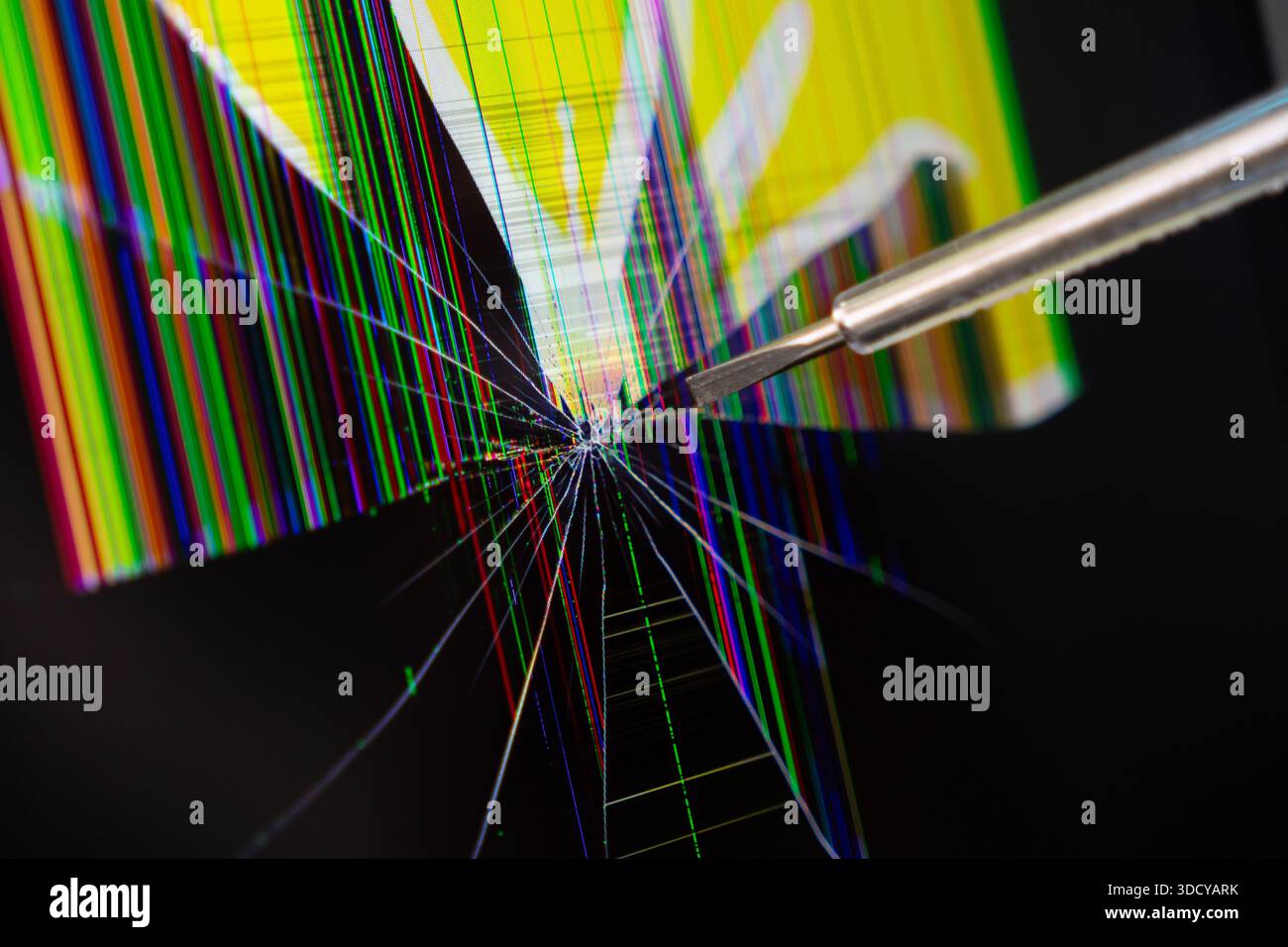 Eine detaillierte Aufnahme eines stark zerstörten digitalen Bildschirms mit lebendigen toten Pixeln und komplexen Rissen, ein Präzisionswerkzeug, das auf dringende elektronische Geräte hinweist Stockfoto
