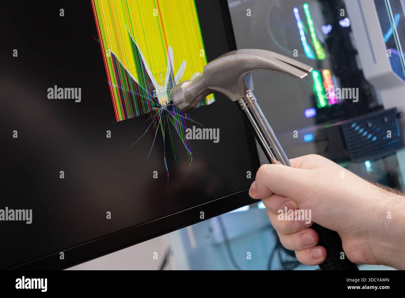 Nahaufnahme einer menschlichen Hand, die einen schweren Metallhammer hält, der einen schwarzen Computermonitor zerschmettert, mit bunten gebrochenen Pixeln und einem digitalen Symbol Stockfoto