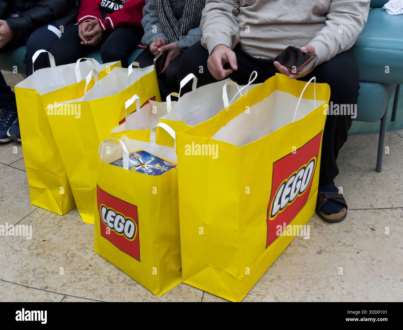 Kent, Großbritannien, 26. Dezember 2025. Gelbe Einkaufstaschen der Marke LEGO werden vor Käufern platziert, die auf einer Bank im Bluewater Shopping Centre sitzen. Credit: Glosszoom/Alamy Live News Stockfoto