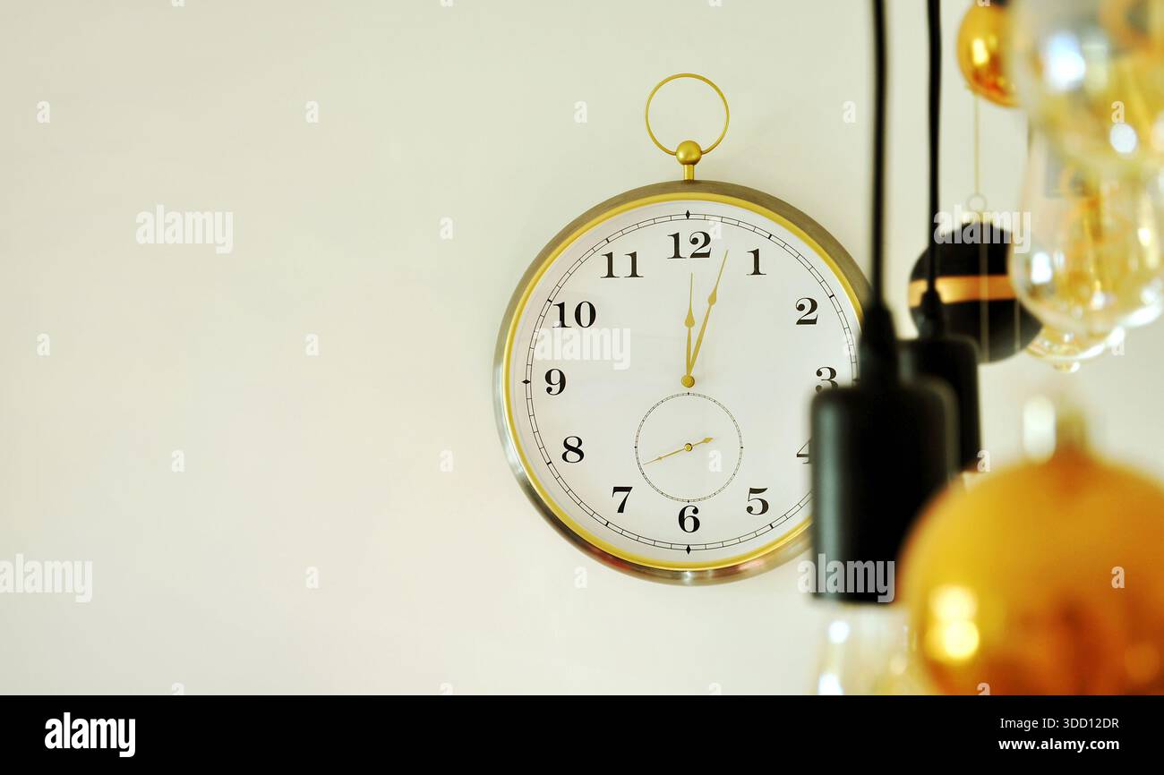 Die Uhr schlägt zwölf, drei Minuten nach Mitternacht. Rund um die Uhr an einer hellen Wand, Mitternacht, Silvesterkonzept. Fragment der häuslichen Umgebung Stockfoto