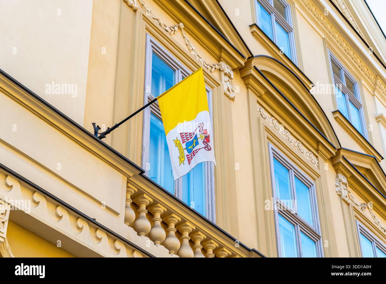 Gelbe Flagge des Vatikans an der Wand des Gebäudefensters Stockfoto