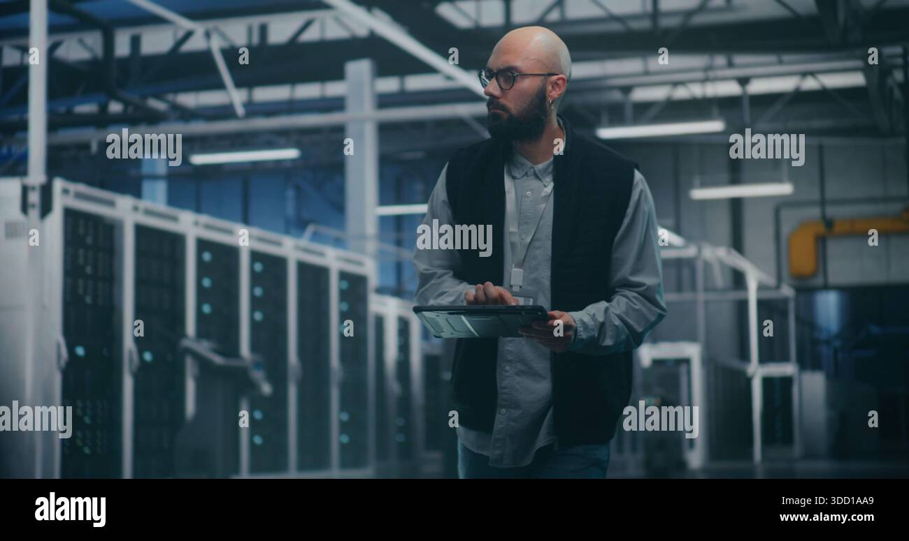 Ingenieur, der Software im Rechenzentrum nutzt. Professional Male Engineer verwendet eine spezielle App auf Tablet, um die Leistung von Enterprise-Servern zu überwachen. Moderne IT-Tools und technische Überwachung. Stockfoto