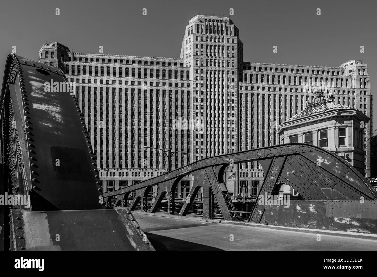 Monochromansicht der Art-Deco-Fassade des Merchandise Mart, eingerahmt hinter dem geschraubten Stahlbogen der Franklin Street Bridge in Chicago. Stockfoto