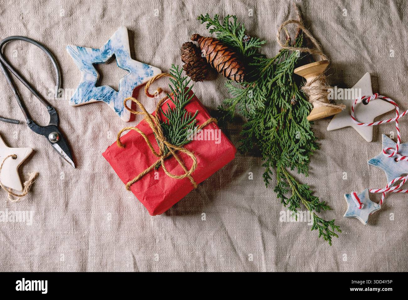 Weihnachtsdekoration Keramiksterne weiß und blau glasiert, verschiedene Größen, Geschenkboxen in Bastelpapier, grüne Zweige über Leinentuch als Hintergrund. Weihnachten, Neujahr Geschenkverpackung. Flach, Platz. Stockfoto
