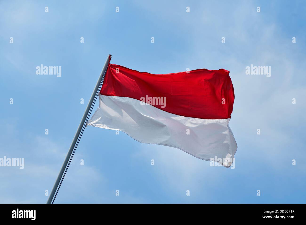 Die Flagge der Republik Indonesien, die rote und weiße Flagge genannt wird, flattert anmutig am blauen Himmel Stockfoto