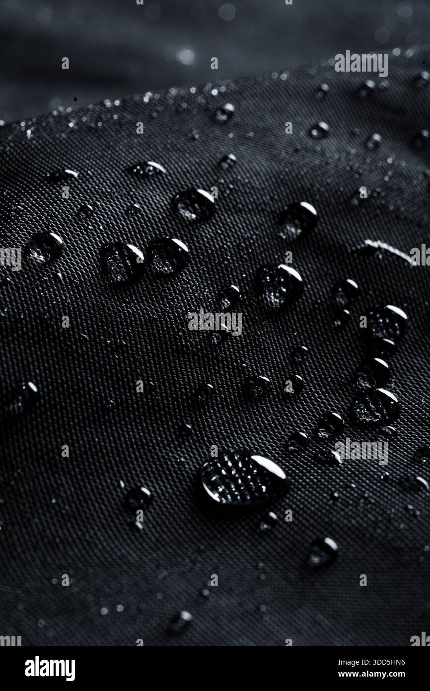 Dunkle Makrostruktur von Wassertröpfchen auf schwarzem wasserdichtem Gewebe Stockfoto