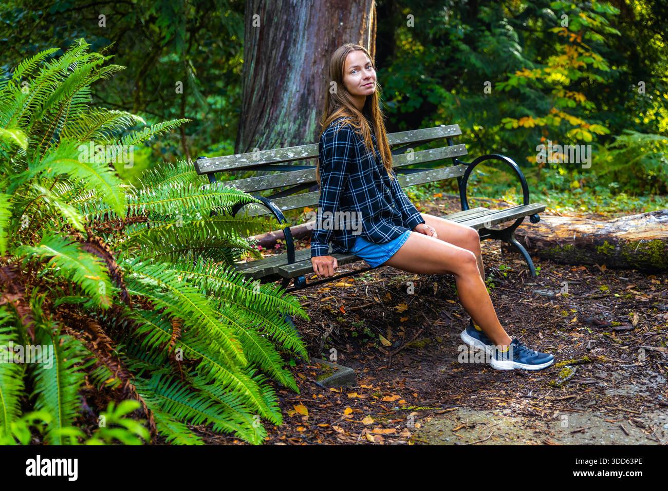 Eine hübsche weibliche Besucherin genießt die üppige, malerische Aussicht auf die botanische Landschaft im Washington Park Arboretum in Seattle. Stockfoto