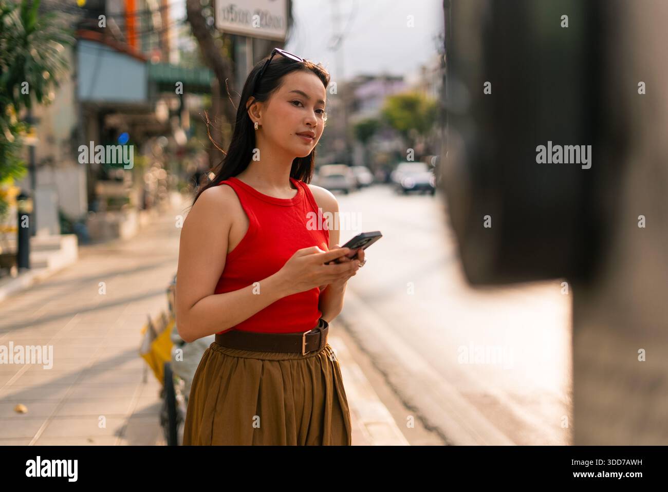 Asiatische Frau, die auf dem Smartphone in der Stadtstraße schreibt und sich mit Technologie beschäftigt Stockfoto