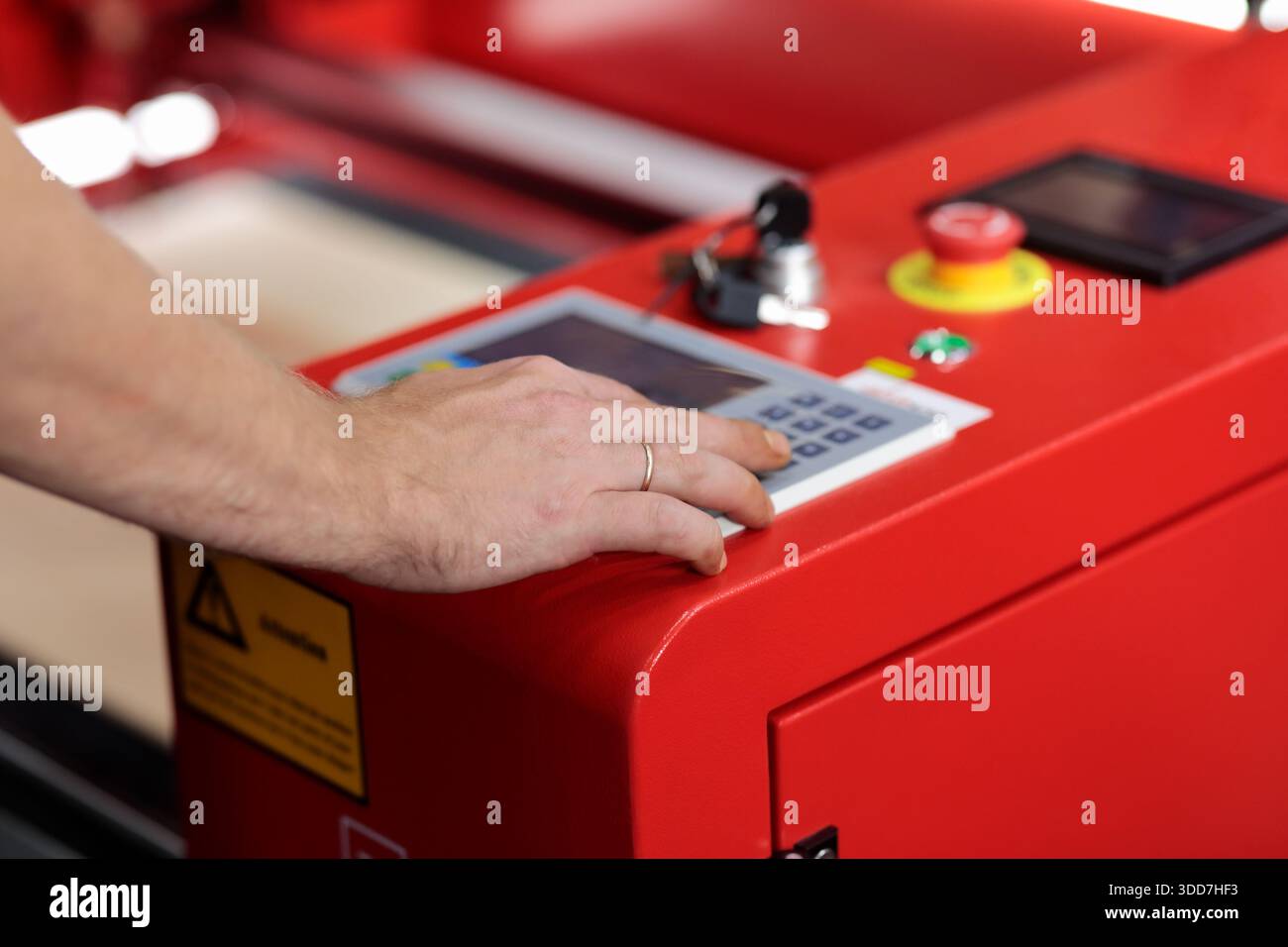 Hand auf dem Bedienfeld automatisierter Industriemaschinen. Drucktaste des Maschinenbedieners auf dem Bedienfeld des automatisierten industriellen Laserschneidens A Stockfoto
