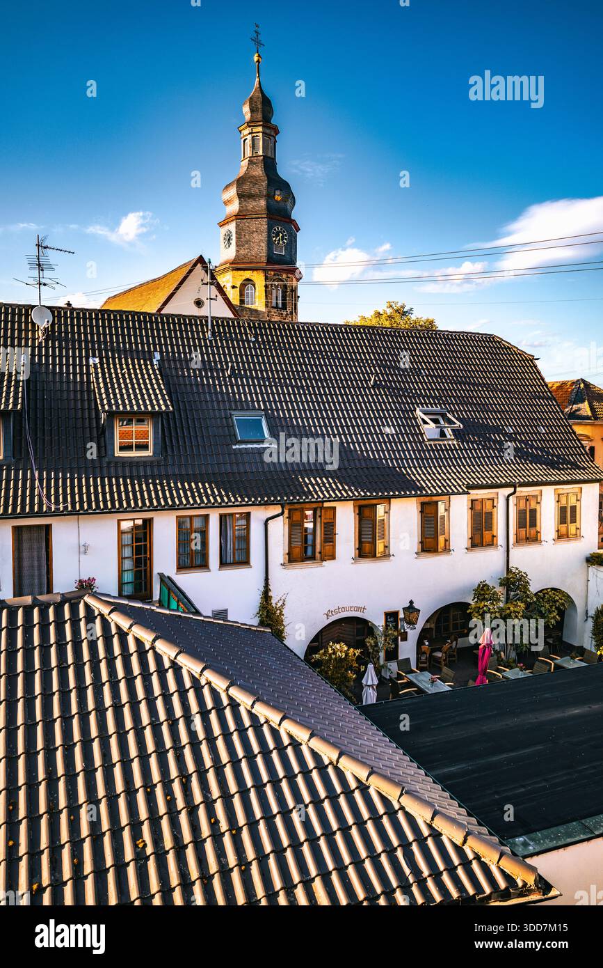 Ein fesselnder Blick auf eine malerische europäische Stadt mit einer Kirche mit Uhrenturm und einem Restaurant mit einem markanten Bogeneingang. Stockfoto